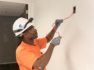 Electrician in hard hat wiring a remodeled home