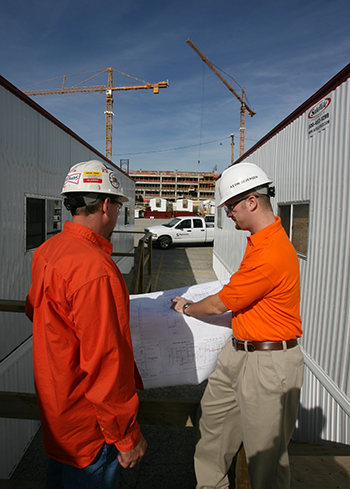 Electricians in hard hats looking over plans