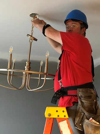 Electrician hanging light fixture
