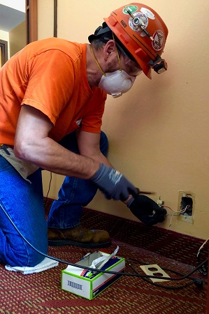 Electrician with hard hat and mask working on wiring