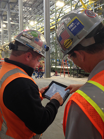 Electricians in hard hats looking at a tablet
